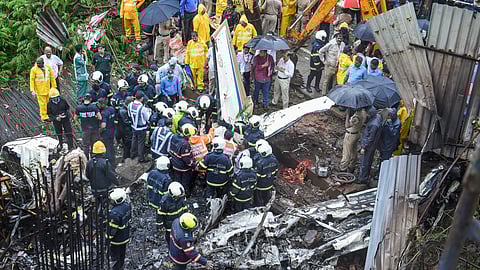 Mumbai rescue personnel stand near the debris of the chartered plane that crashed in Ghatkopar's Jivdaya lane( Photo | PTI)
