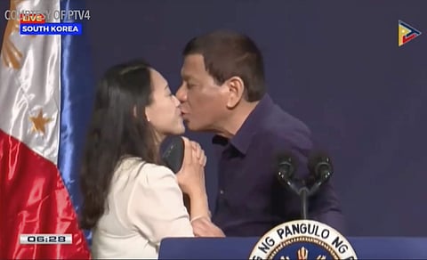 In this video from PTV taken Sunday, June 3, 2018, Philippines President Rodrigo Duterte leans in to kiss a Filipino worker at the podium during a town hall-style meeting with overseas Filipino workers in Seoul, South Korea. | AP