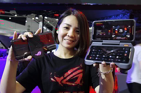 An employee displays two ASUS ROG phones with Twinview Dock, right, and Aero Active Cooler during the Computex Taipei, one of the world's largest IT expos, in Taipei, Taiwan, Tuesday, June 5, 2018. | AP