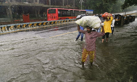 People wade through a flooded street at Jambli Naka after heavy rains, in Thane on Tuesday. (Photo | PTI)