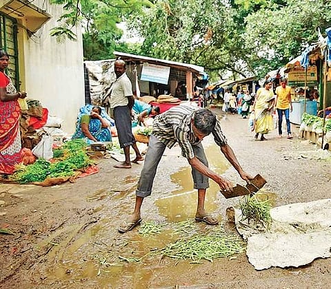 A vegetable vendor in Alwal Rythu bazar removes cluster beans which fell on the road inundated with water | Vinay Madapu