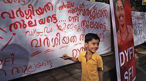 A boy writing on a poster which was set up to pay tribute to SFI leader Abhimanyu, who was murdered on the Maharaja’s College campus in Kochi, on Thursday | Melton Antony