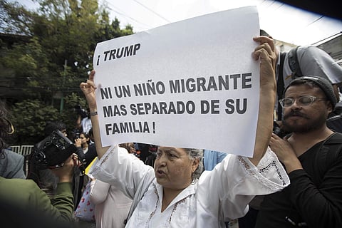 A woman holds up a protest poster with a message that reads in Spanish: 'Trump, Not one more immigrant child separated from her family!,' outside the campaign headquarters of Mexican President-elect Andres Lopez Obrador, in Mexico City | AP