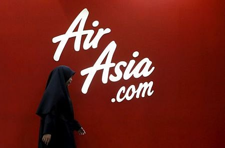 A woman walks past the Air Asia logo at its sales centre in Kuala Lumpur, Malaysia. ( File photo | Reuters)