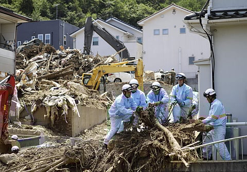 Rescuers remove driftwood from a residential area after flooding caused by heavy rains (Photo | AP)