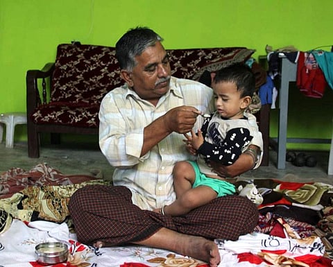 Mohammed Osman, the father of Mohammed Azam who was lynched in Bidar, trying to pacify and make Azam's son Ahmed to eat food at their residence in Errakunta at Barkas in Hyderabad. (Photo | Sathya Keerthi/EPS)