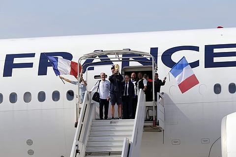 French goalkeeper Hugo Lloris holds the cup next to head coach Didier Deschamps, left, as the French soccer team arrives at Charles de Gaulle airport. | AP