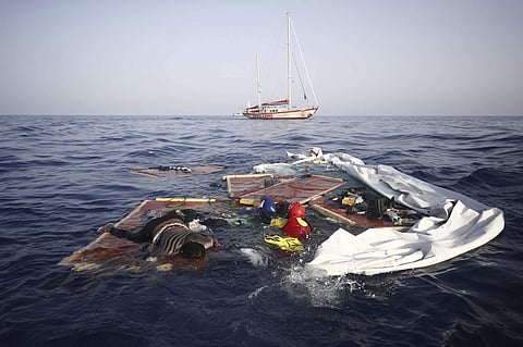 Rescue workers from the Proactiva Open Arms Spanish NGO retrieve the bodies of an adult and a child amid the drifting remains of a destroyed migrant boat off the Libyan coast. (Photo | AP)