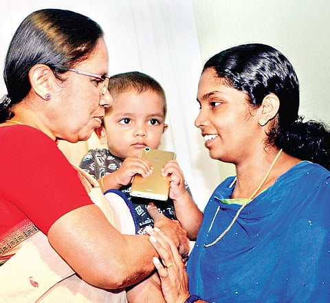 Health Minister K K Shylaja holds Sidharth, the youngest child of nurse Lini Puthussery who died due to the Nipah virus, while talking to her sister Liji in Kozhikode on Sunday | Manu R Mavelil