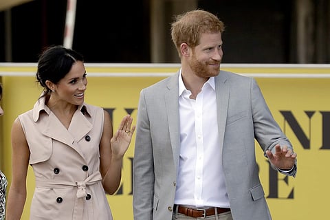 Britain's Prince Harry, right, and his wife Meghan the Duchess of Sussex wave at onlookers as they arrive for their visit to the launch of the Nelson Mandela Centenary Exhibition, marking the 100th anniversary of anti-apartheid leader's birth, at the Quee