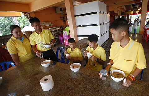 Coach Ekkapol Janthawong, second from left, and members of the rescued soccer team enjoy their breakfast before a Buddhist ceremony. (File |AP)