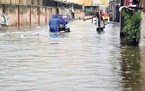 Commuters wade through a waterlogged road in Cuttack | Express