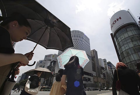 People shade themselves from the heat of the sun with umbrellas as they pass the Ginza shopping district in Tokyo, Monday, July 23, 2018. | Associated Press