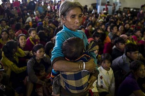 An elderly woman carries a child while other residents displaced by massive flood waters from the collapsed dam seek shelter in Paksong town in Champasak province on July 25, 2018. The bodies of 17 people have been recovered after a dam collapse led to fl
