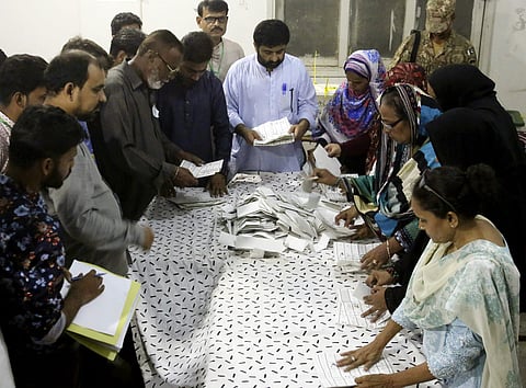 Pakistani election staff count the votes following polls closed at a polling station for the parliamentary elections in Karachi, Pakistan. (Photo | AP)