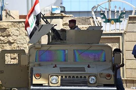 A member of the Iraqi security forces mans a turret in a humvee outside a warehouse where ballots from the May parliamentary election are stored in the capital Baghdad on July 9, 2018, as the electoral commission continued a partial recount of ballots in 
