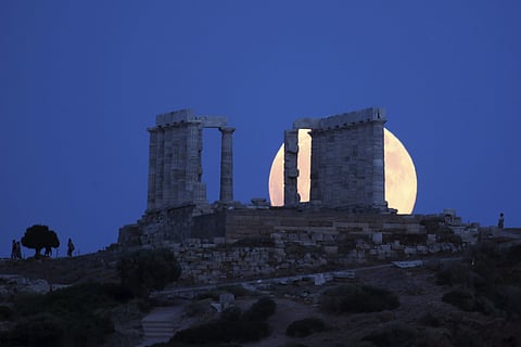 A full moon rises behind the ancient temple of Poseidon in cape Sounio, about 65 kilometers (40miles) south of Athens, Friday, July 27, 2018. | AP