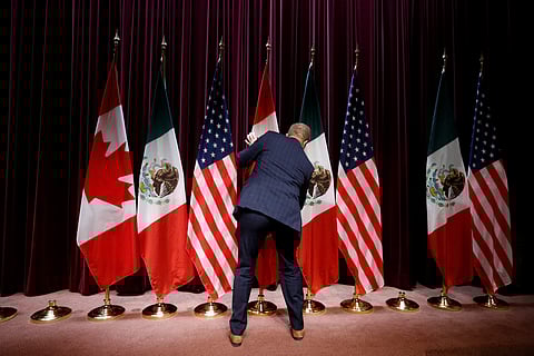 A staff member moves flags at the close of the third round of NAFTA talks involving the United States, Mexico and Canada in Ottawa, Ontario, Canada. (Photo | Reuters)