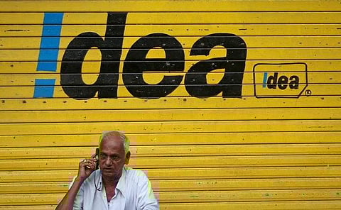 A man speaks on his mobile phone as he sits in front of a shop displaying the Idea Cellular Ltd's logo on its shutter in Mumbai. (File | Reuters)