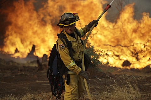 A firefighter makes a stand in front of an advancing wildfire as it approaches a residence Saturday, July 28, 2018, in Redding ,California.  ( Photo | AP)