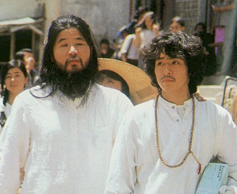In this undated file photo, cult guru Shoko Asahara, left, of Aum Shinrikyo walks with Yoshihiro Inoue, then a close aid, in Tokyo. Japanese media reports say on Friday, July 6, 2018, Asahara, who has been on death row for masterminding the 1995 deadly To