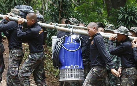 Soldiers carry a pump to help drain the rising flood water in a cave where 12 boys and their soccer coach have been trapped since June 23, in Mae Sai, Chiang Rai province, in northern Thailand Friday, July 6, 2018. Thai authorities are racing to pump out 