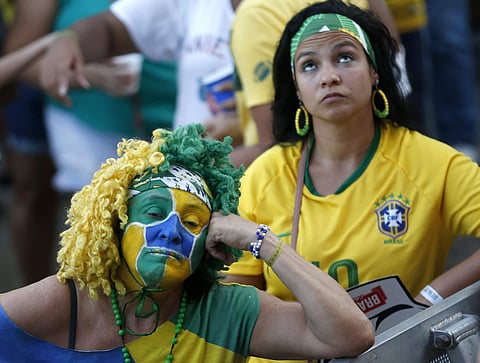 Brazil soccer fans react after their team lost 2-1 to Belgium in a World Cup quarter final soccer match. | AP