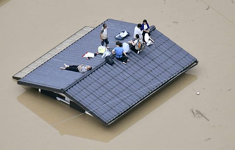 People waif to be rescued on the top of a house almost submerged in floodwaters caused by heavy rains in Kurashiki. (Photo | AP)