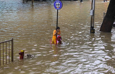 A woman tries to cross a flooded road in Mumbai (Photo | PTI)