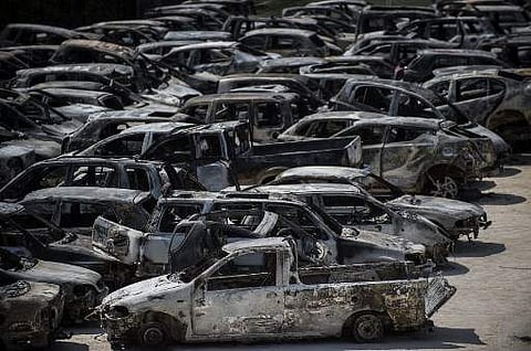 A picture taken on July 26, 2018 shows burnt cars parked outside a football stadium following a wildfire at the village of Rafina, near Athens. Greece was counting the cost on July 26 of its deadliest wildfires in living memory, as emergency crews searche