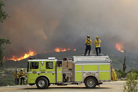A fire crew from San Luis Obispo County keeps an eye on an advancing wildfire from the perimeter of a residence Tuesday, July 31, 2018, in Lakeport, California. ( Photo | AP)