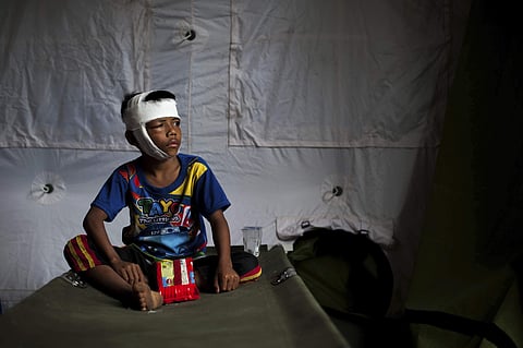 A boy who was injured in Sunday's earthquake sits on a folding bed at a makeshift hospital in Kayangan, North Lombok, Indonesia. (Photo | AP)