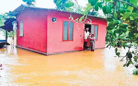 A family in Mananthavady in Wayanad peering out from their house which is surrounded by the water from the overflowing Kabini river