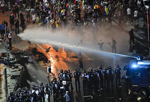 Riot police use a water canon during a charge to clear the square during protests outside the government headquarters, in Bucharest. (Photo | AP)