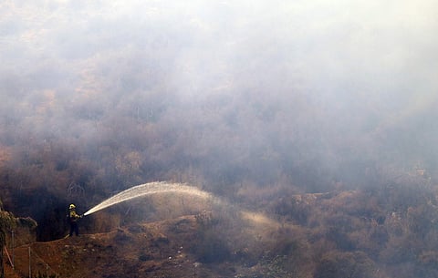A firefighter hoses down hot spots caused by a wildfire Friday, Aug. 10, 2018, in Lake Elsinore, California. (Photo | AP)