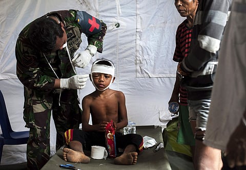 A military paramedic tends to a boy who's head was injured from Sunday's earthquake at a makeshift hospital in Kayangan, Lombok Island. (Photo | AP)
