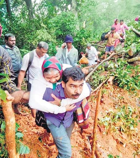 Locals help passengers of a KSRTC bus after they were hit by a landslide near Bisle on Wednesday