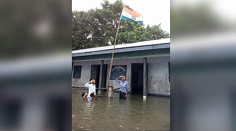 The viral photo of the nine-year-old boy saluting the Tricolour in chest-deep flood water in an Assam school on Independence Day last year. (Photo | Twitter)