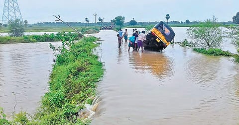 Villagers try to pull out an autorickshaw stuck on the water logged Godavari bridge in Khammam on Sunday. Several places in the town have been inundated with rain water | Express photo