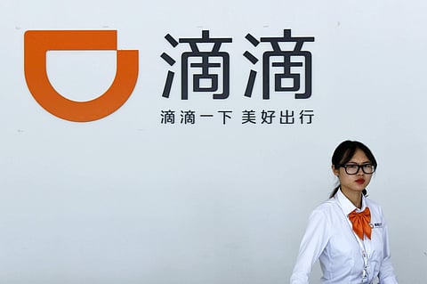 In this June 13, 2016, photo, a receptionist walks by front desk of the service station for Didi Chuxing's drivers in Hangzhou in east China's Zhejiang province. Chinese ride-hailing giant Didi Chuxing has fired two executives and will suspend one of its 