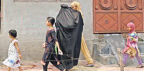 Camera-Shy: A burqa-clad woman tries to shield her friend from being photographed in Muzaffarnagar that remains deeply divided along communal lines. (Photo| Parveen Negi/EPS)