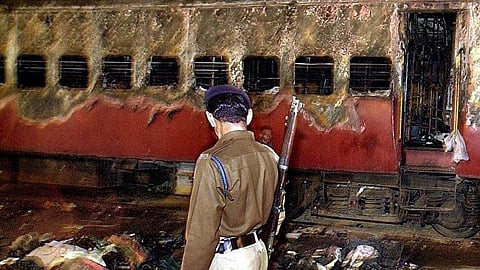 A policeman looks over a burnt coach and belongings of people at Godhra station, on 28 February 2002, some 200 km from Ahmadabad.