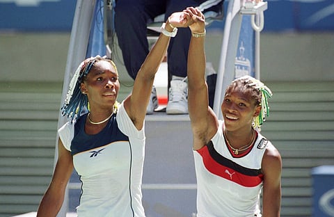 In this Jan. 21, 1998 photo, Venus Williams (L) and sister Serena raise their arms after their center court match at the Australian Open Tennis Championships in Melbourne | AP