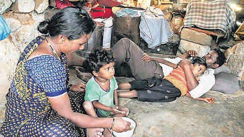 A woman feeds her child sitting in a cramped room at Keshav Nagar, in Hyderabad  on Monday. | s senbagapandiyan