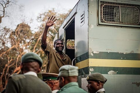 A supporter of the opposition Movement for Democratic Change (MDC) Alliance gestures the party's symbol while being escorted to a prison truck from a magistrate's court in Harare. (Photo | AFP)