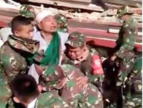 In this image made from video released by the Indonesian military, a man is carried by Indonesian military after they rescued him from a collapsed mosque in the powerful earthquake, Tuesday. (Photo| AP)