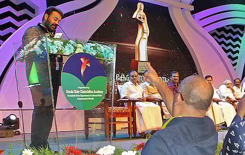 Best Supporting Actor award winner Alencier gestures a symbolic protest while chief guest  Mohanlal delivers his speech at the Kerala State Film Awards Nisagandhi on Wednesday night, 08 august 2018. | EPS/ BP Deepu
