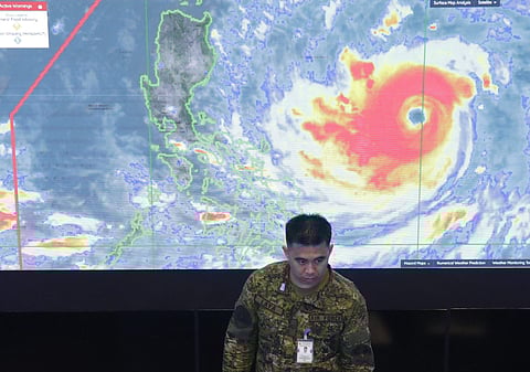 A member of the Philippine Air Force stands in front of a satellite image of Typhoon Mangkhut, locally named Typhoon Ompong, at the National Disaster Risk Reduction and Management Council operations center in metropolitan Manila, Philippines on Thursday, 
