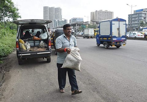 Dadarao Bilhore carrying a sack filled with building materials to fill up a pothole on the Western Express highway in Mumbai. (Photo | AFP)