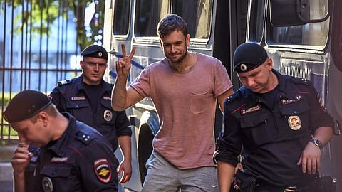 Member of the Pussy Riot punk group Pyotr Verzilov (C) gestures as he walks with police during a court hearing at a courthouse in Moscow, on July 31, 2018, as members of the Russian protest-art group are accused of disturbing public order after invading t